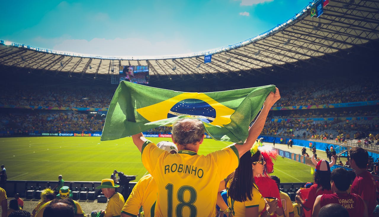 Services Excited Brazilian fans holding flag at soccer match in vibrant stadium atmosphere.