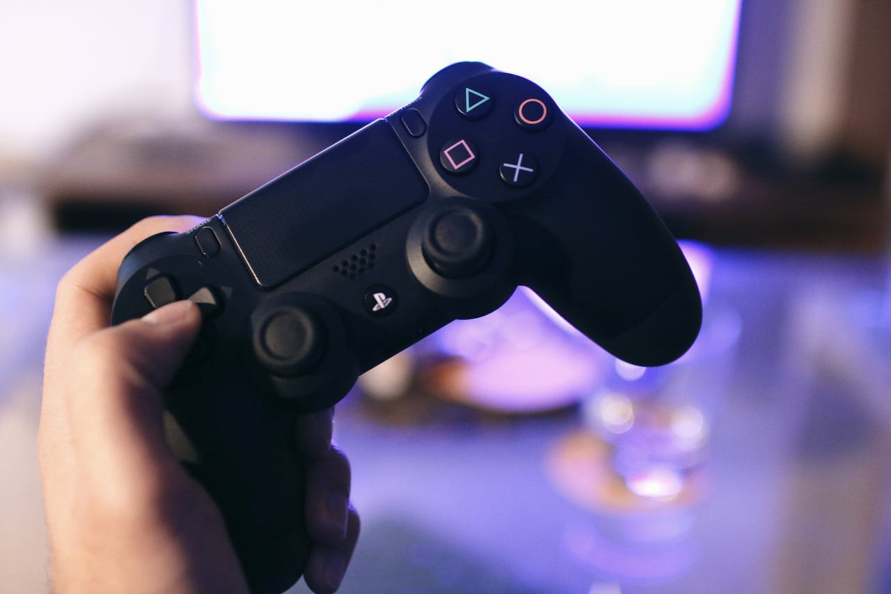 Home Person holding a gaming controller, blurred screen in background.